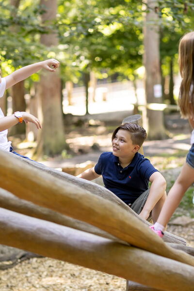 Zwei Jungen und ein Mädchen klettern auf einem Spielgerät aus Baumstämmen im Wildpark Knüll